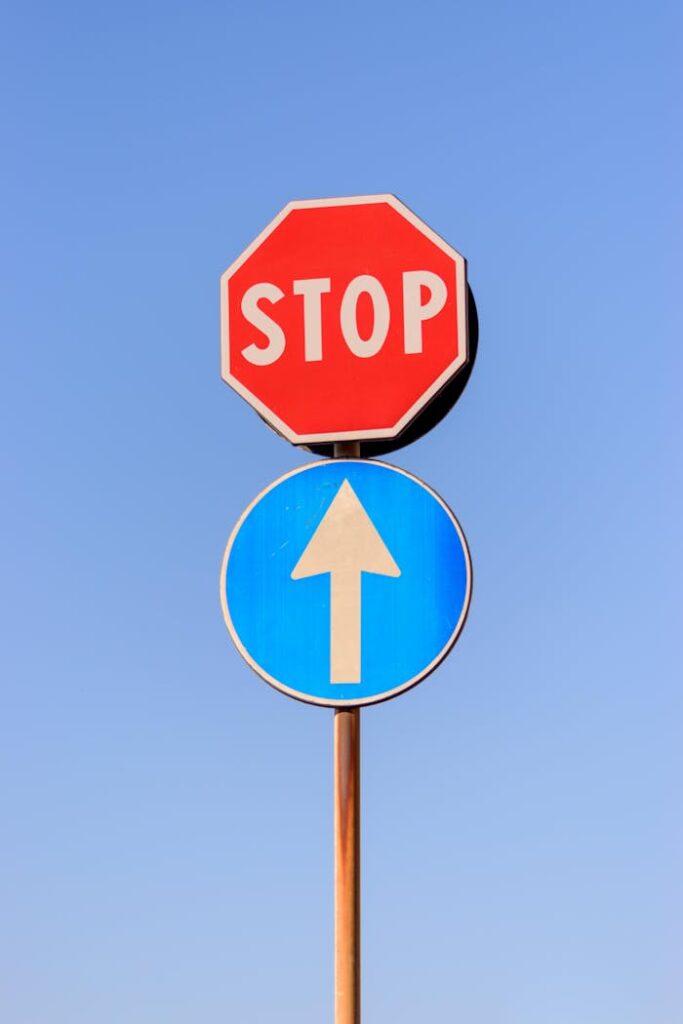 pexels-photo-12274676 A red stop sign and blue forward arrow against a clear blue sky.