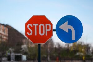 Close-up of outdoor stop and left turn traffic signs with blurred nature background.